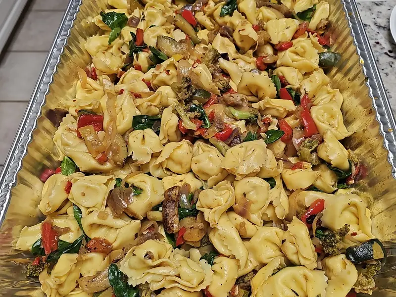 Catering tray of tortellini with roasted vegetables and spinach
